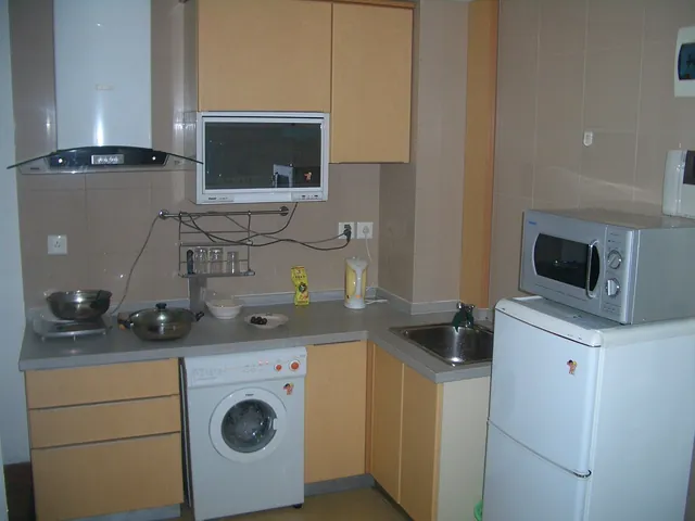 Apartment kitchen fitted with a Haier washer, refrigerator and microwave