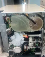 Dishwasher with the lower panel removed showing the sump and pump